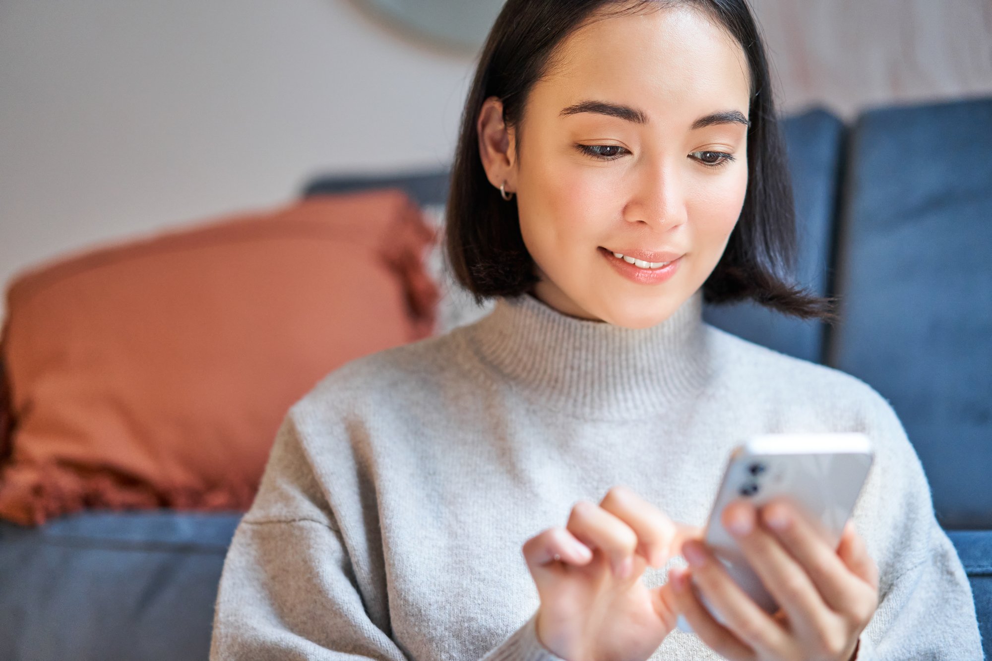 portrait-smiling-asian-woman-sits-home-uses-smartphone-app-orders-delivery-messages-someone